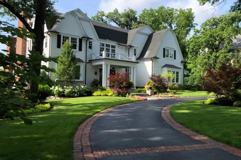 front of house with long driveway and landscaping 