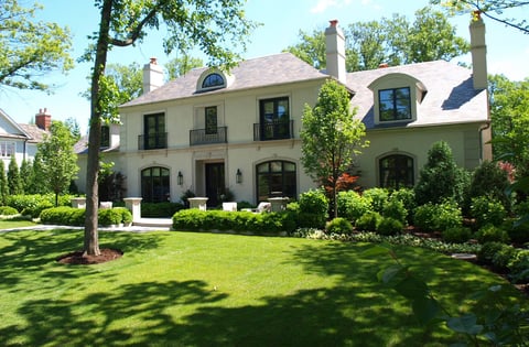 large front yard with green grass and flower beds